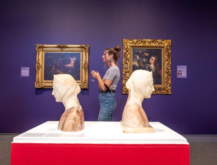 A student standing between two busts at the museum of art